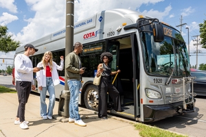 Four passengers about to board a COTA mainstream vechicle in a suburb of Columbus, Ohio.